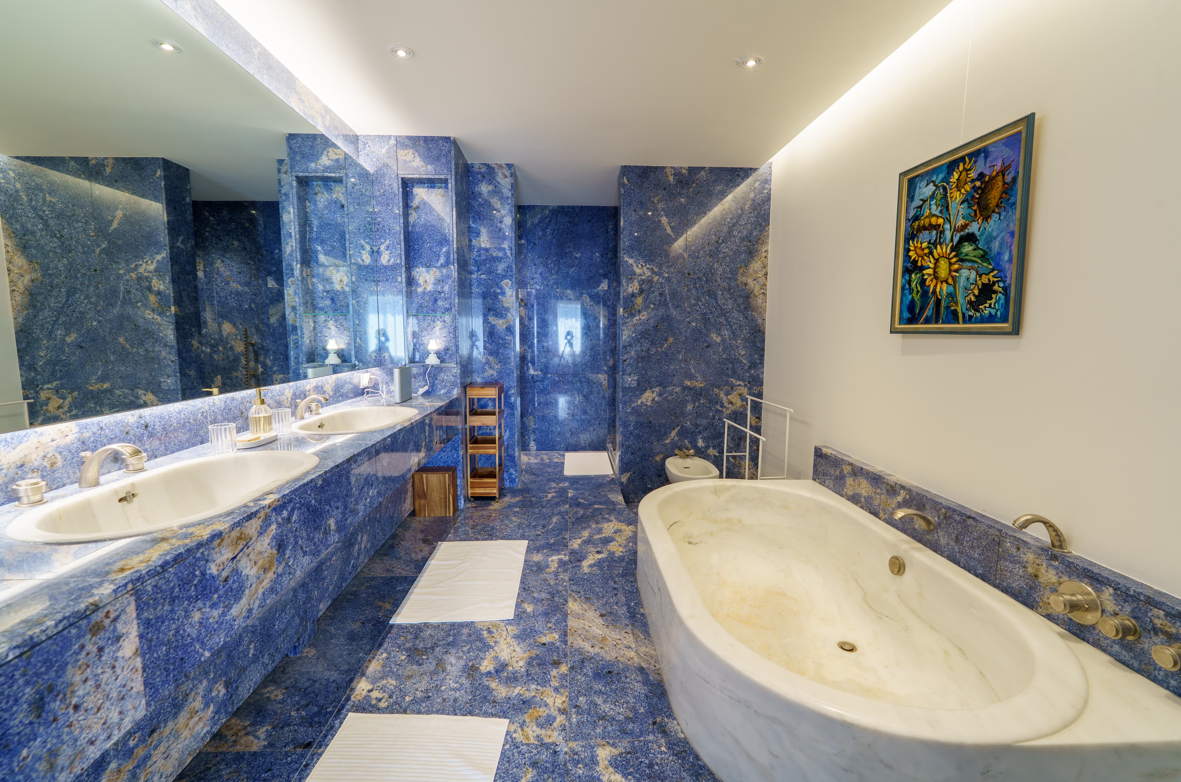 En-suite bathroom in blue marble, with a stone bath set into a marble surround