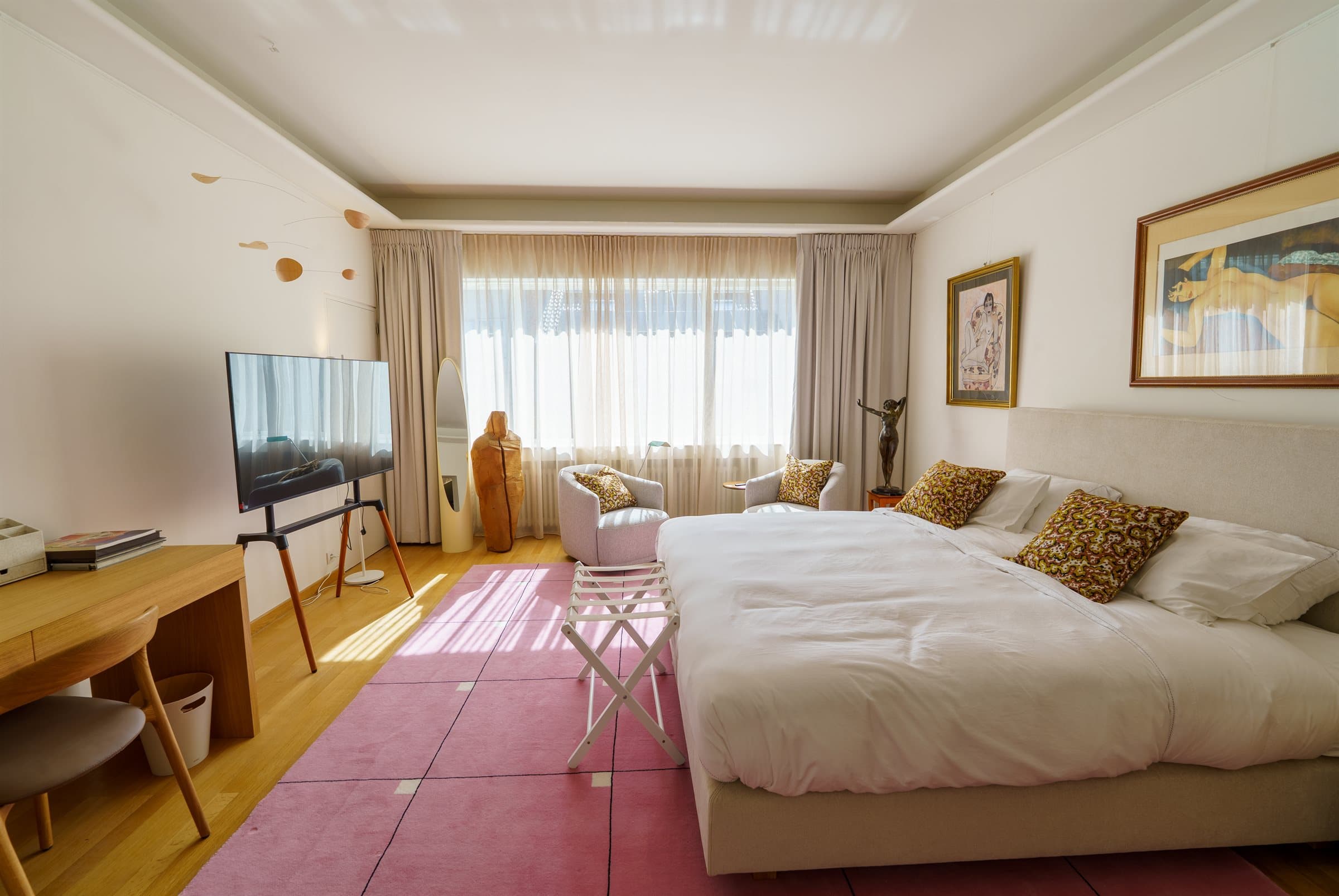 Second-floor en-suite bedroom with a large bed, a rose rug and a seating corner by the window