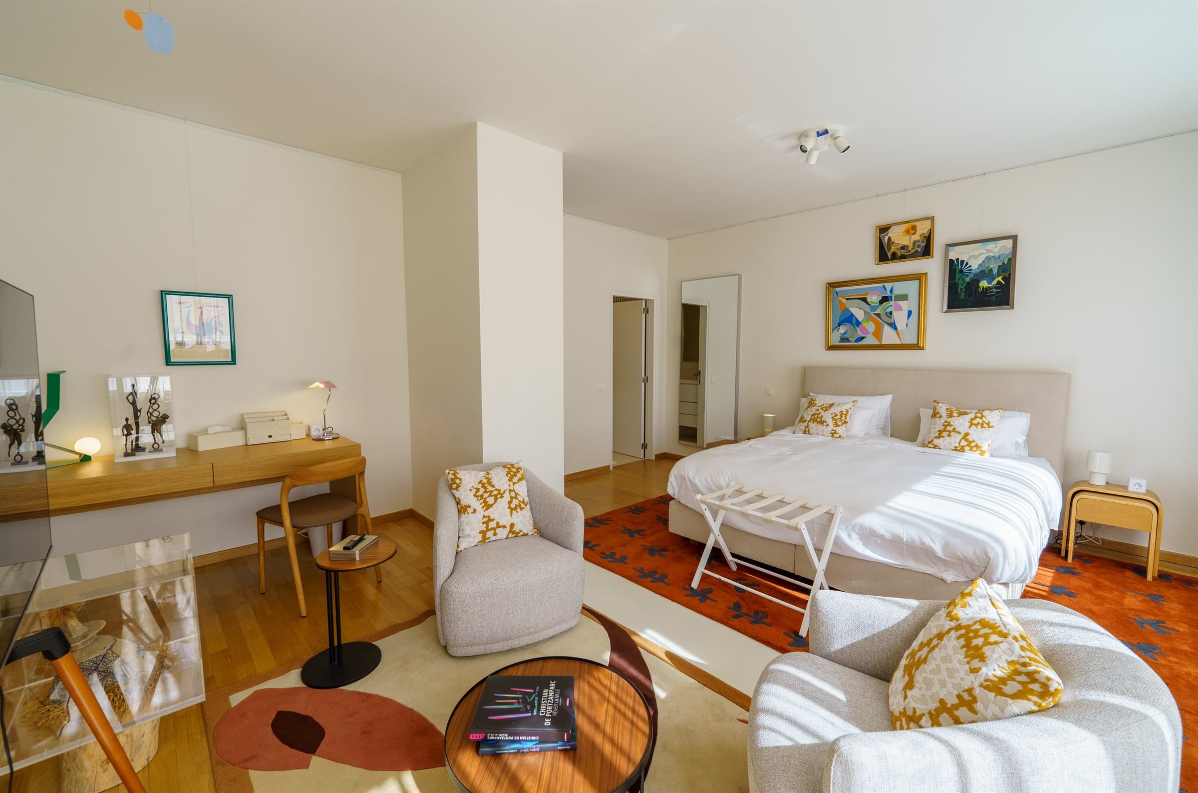 Second-floor en-suite bedroom with a writing desk and a seating area hung with original art