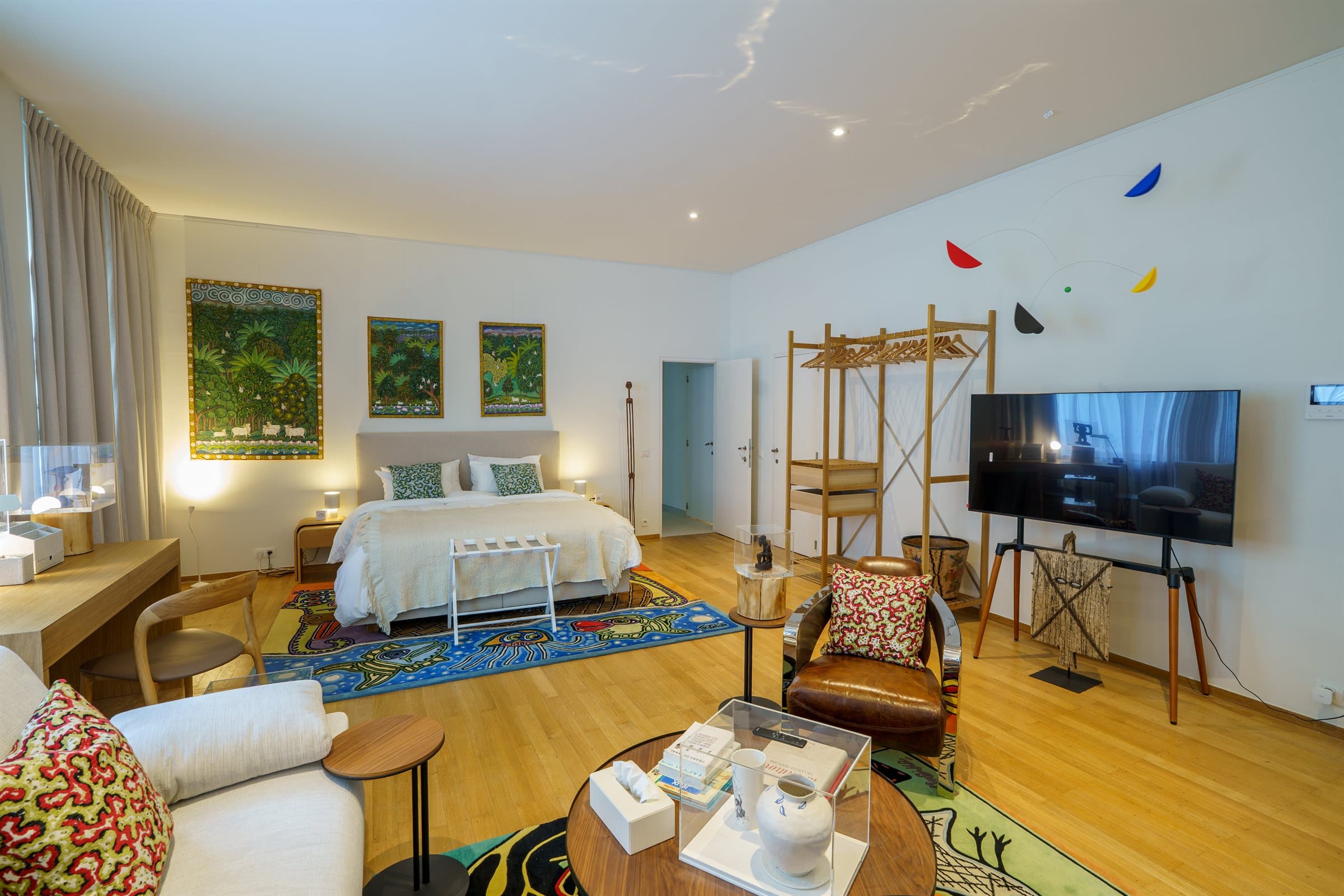 Ground-floor en-suite bedroom with original botanical paintings and a sitting area on a colorful rug