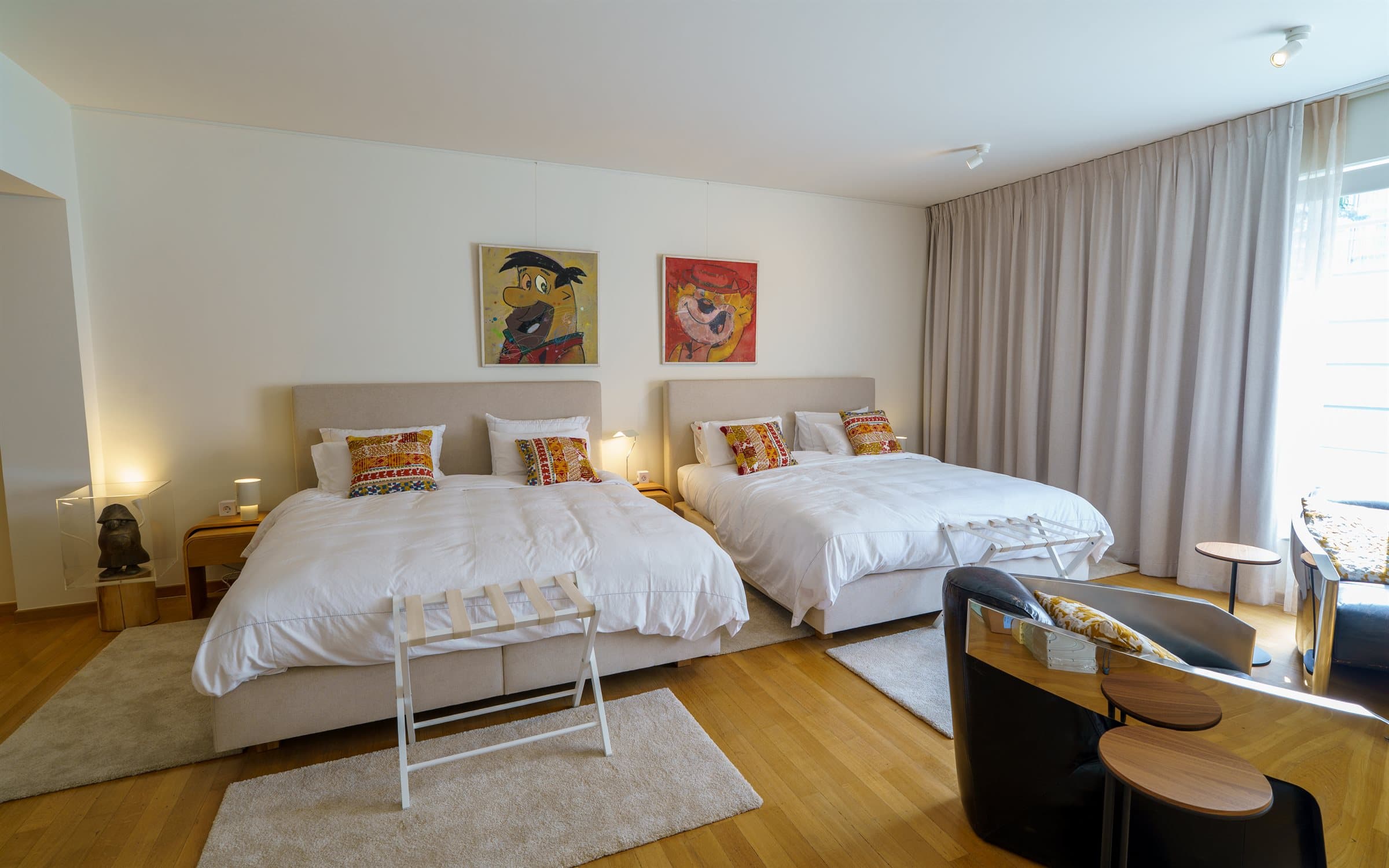 Ground-floor en-suite bedroom with two large beds and pop-art paintings above the headboards