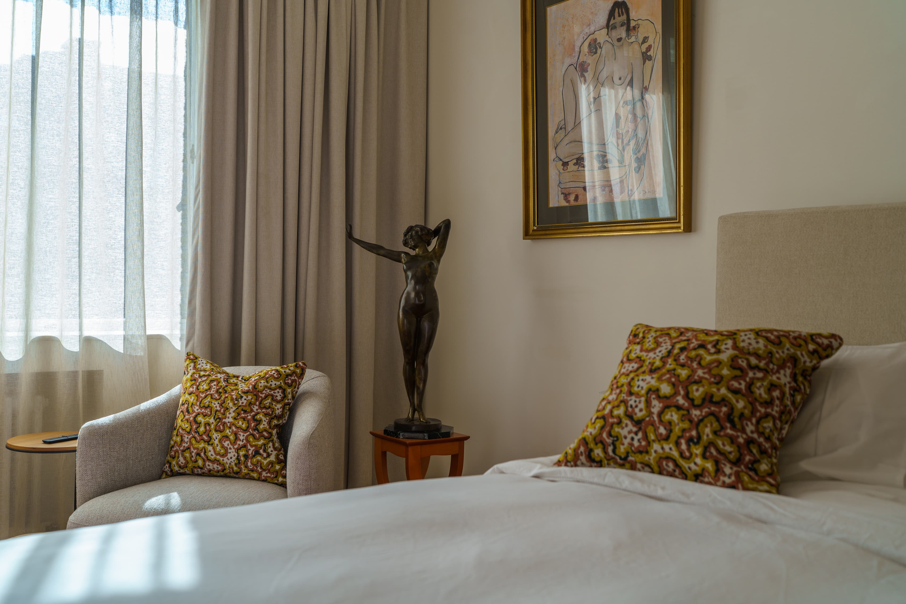 Bronze sculpture and original artwork beside the bed in a second-floor bedroom