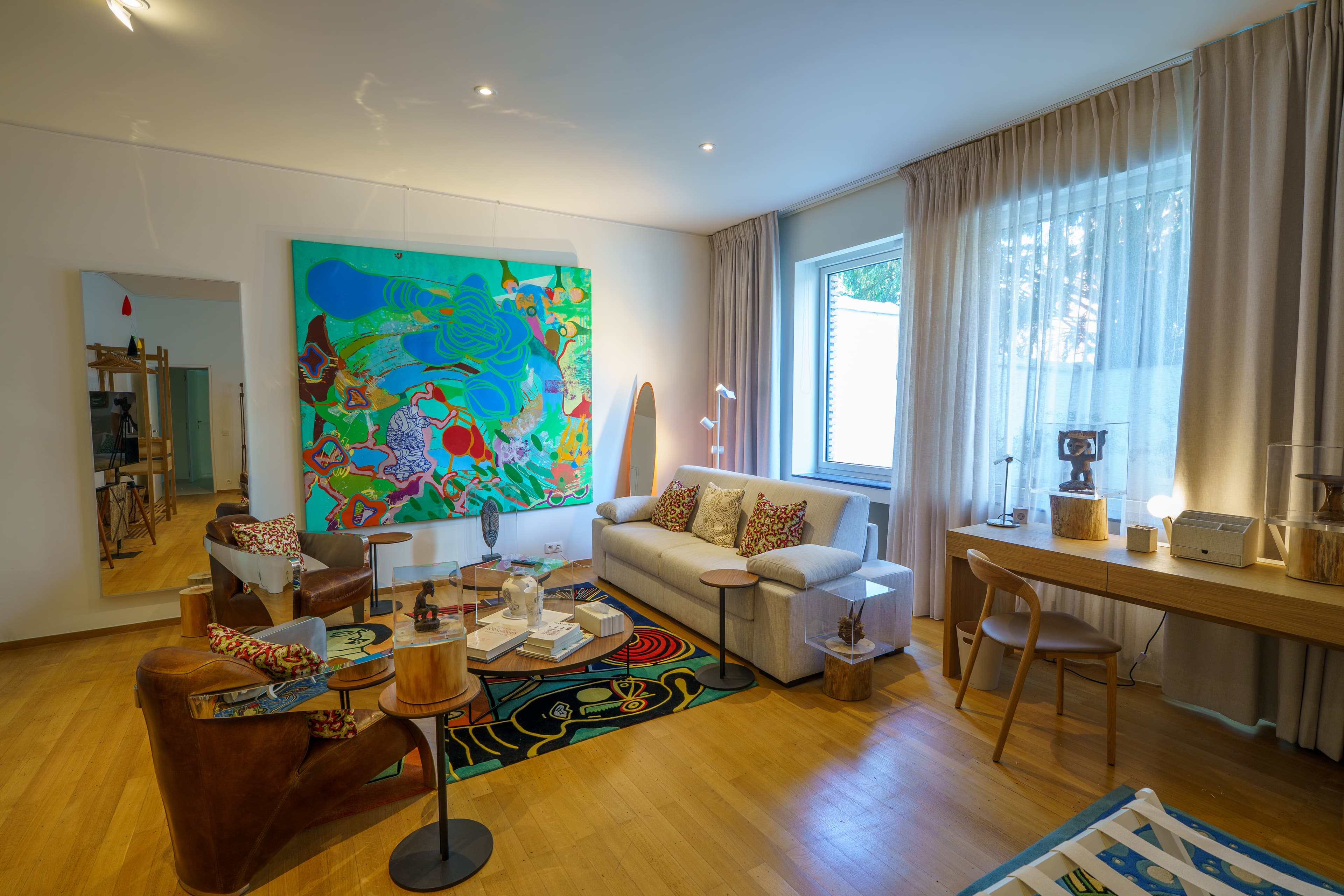 Sitting area with a large colorful painting, a sofa and a desk in a ground-floor bedroom