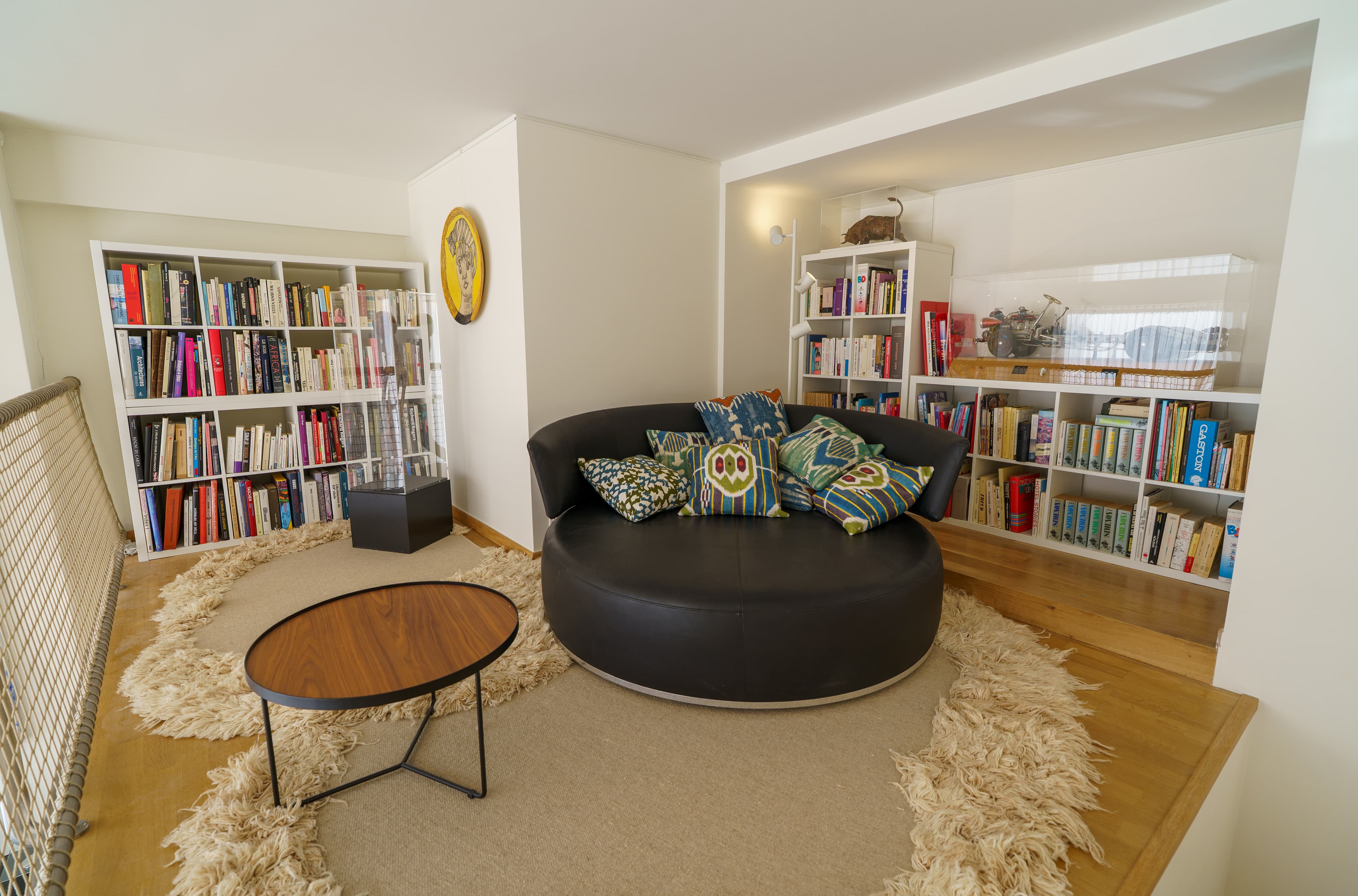 Round black leather reading sofa on a deep rug, surrounded by book-lined shelves