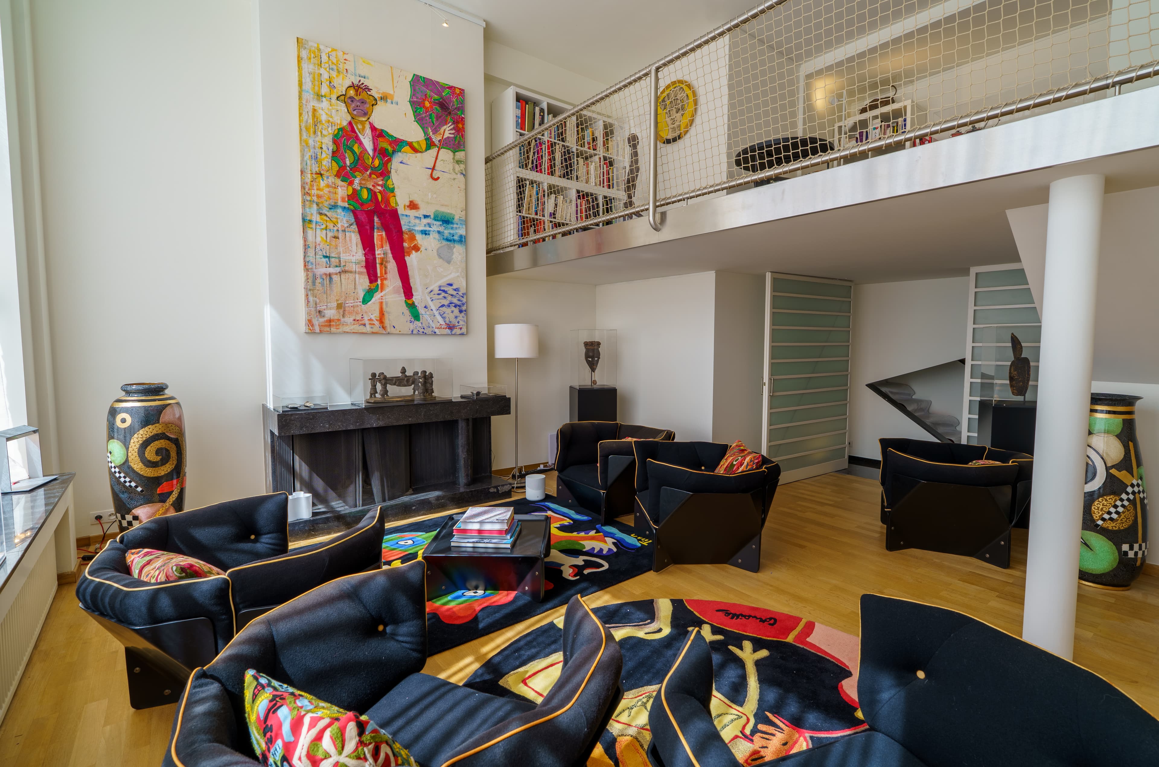 Double-height living room with a curved leather sofa, a pop-art portrait and a mezzanine library