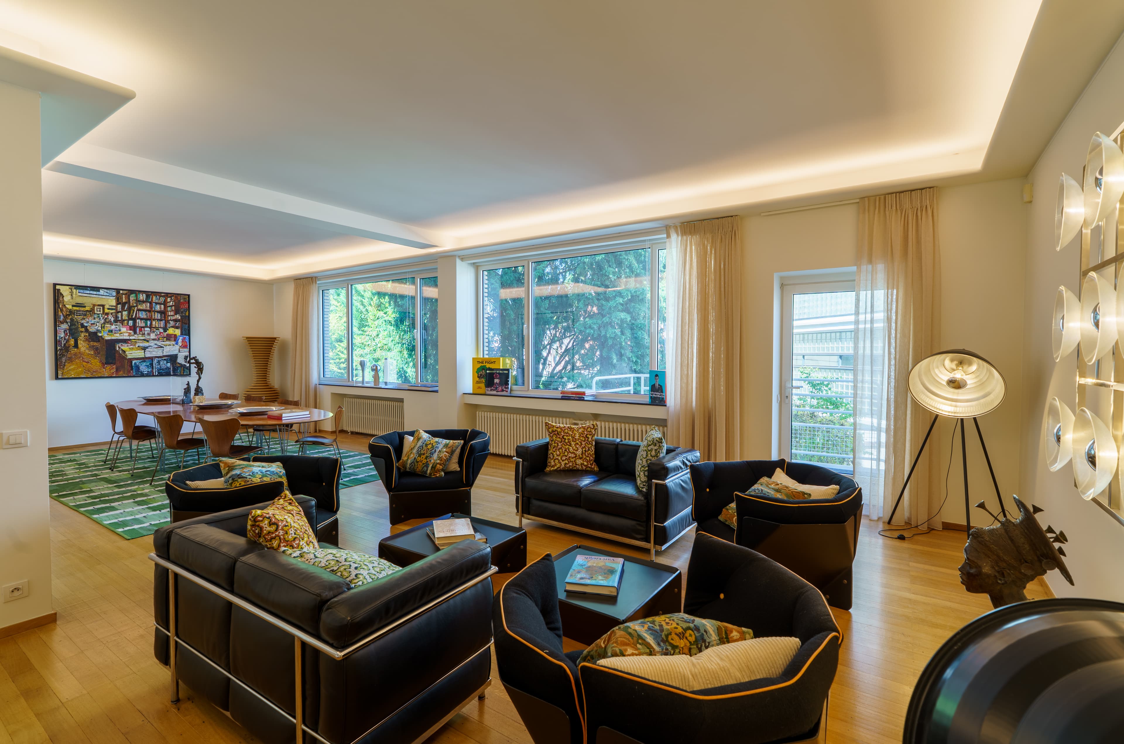 Salon with black leather club chairs, a long table and garden views