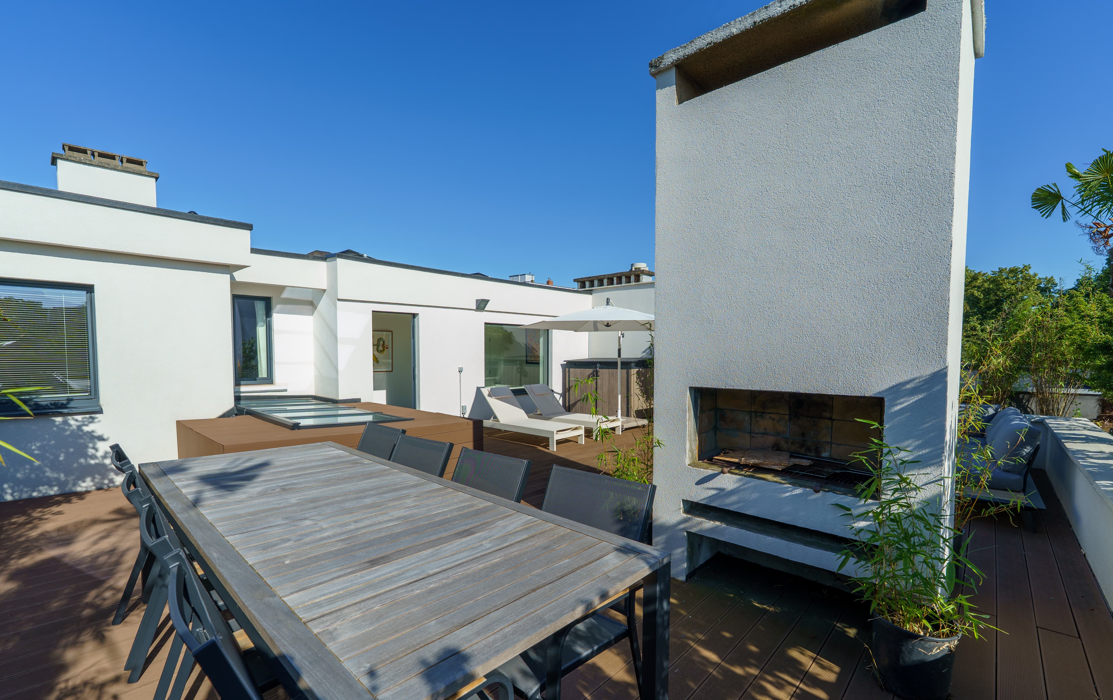 Dining table and outdoor fireplace on the rooftop terrace, laid for a large group